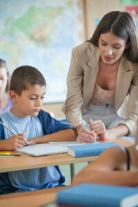 Primary school teacher helping a student in class.